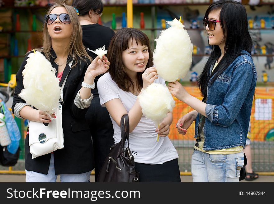 Three girls eating candy floss in city