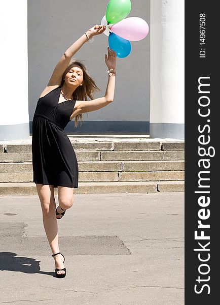 Joyful girl with balloons dancing