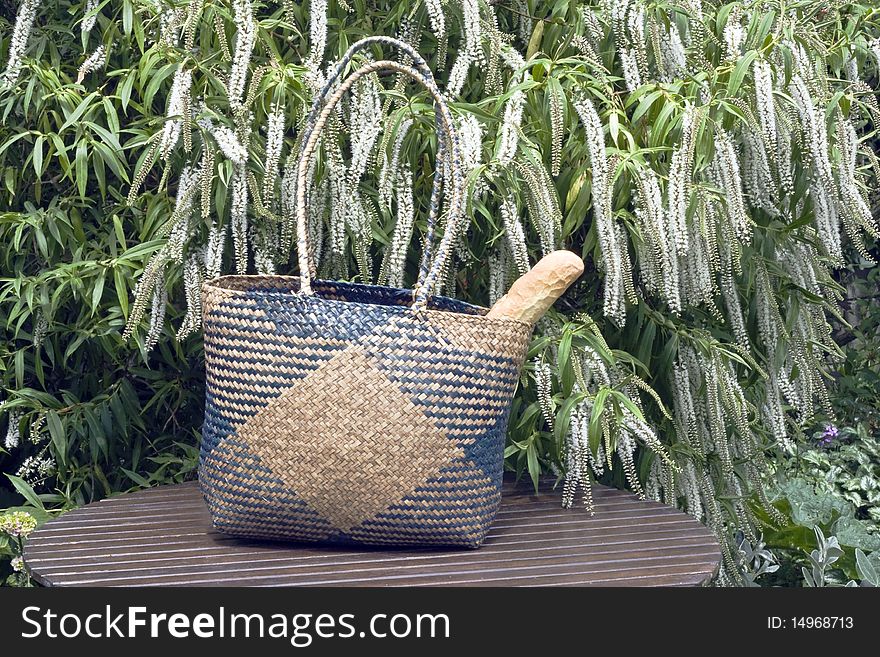 Crispy bread in a wicker shopping basket left on a table in a graden. Crispy bread in a wicker shopping basket left on a table in a graden