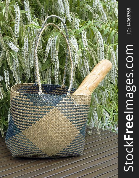 Crispy french bread in a wicker shopping basket left on a table in a graden. Crispy french bread in a wicker shopping basket left on a table in a graden