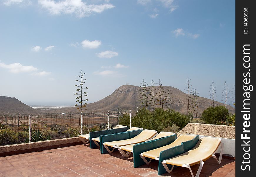 Beach chairs on the background of blue sky and mountains. Tenerife, Canary Islands, Spain.