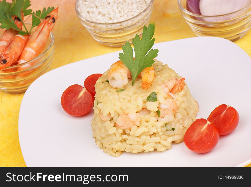 Risotto with shrimps served on a white plate. Rice, shrimps and shallots in small glass bowls are out of focus in the background. Studio shot. Shallow DOF. Risotto with shrimps served on a white plate. Rice, shrimps and shallots in small glass bowls are out of focus in the background. Studio shot. Shallow DOF
