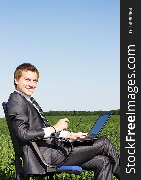Businessman in the field, with a laptop