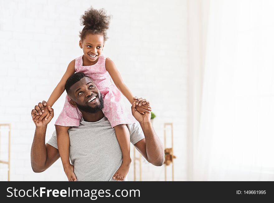 African american father with little daughter on his shoulders, playing and smiling together at home, panorama with free space