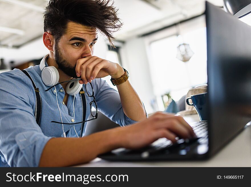 Young modern bearded man working with laptop computer indoors. Computer programmer working at nice coworking space. Young modern bearded man working with laptop computer indoors. Computer programmer working at nice coworking space.