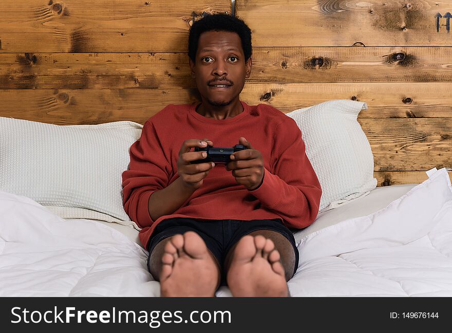 Young afro man having fun playing games in the bed at home