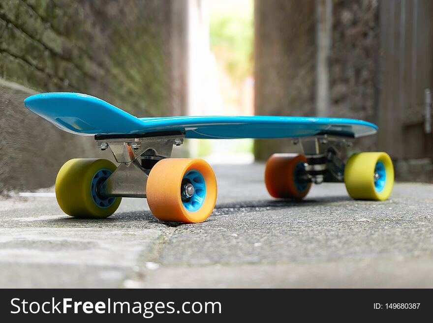 Blue penny with yellow and orange wheels in an alley