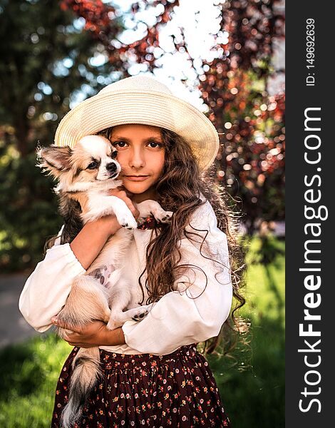 Little nice girl hugging a dog under summer trees in the park outdoors. Little nice girl hugging a dog under summer trees in the park outdoors.