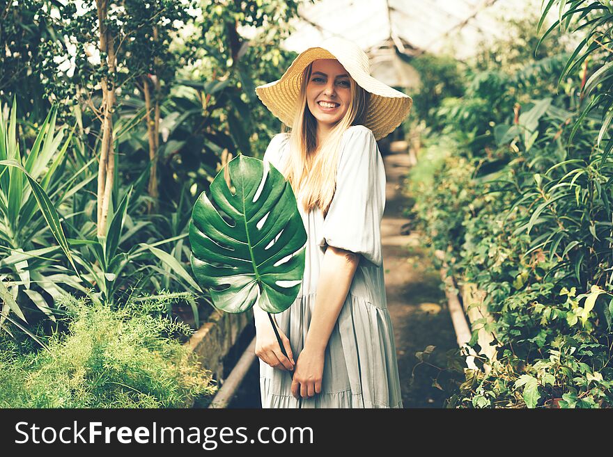 Woman In Tropical Orangery With Monstera Leaf