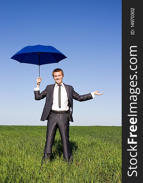 Businessman With Blue Umbrella In Field