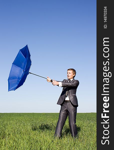 Businessman in a suit claiming the wind. Blue Umbrella. Businessman in a suit claiming the wind. Blue Umbrella