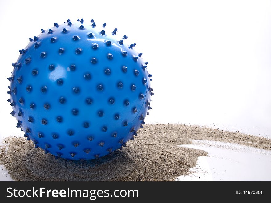 Blue, pointy beach ball, leaving twirling trace in a sand.