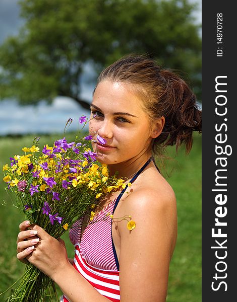 Beautiful Girl is gathering bouquet in a field