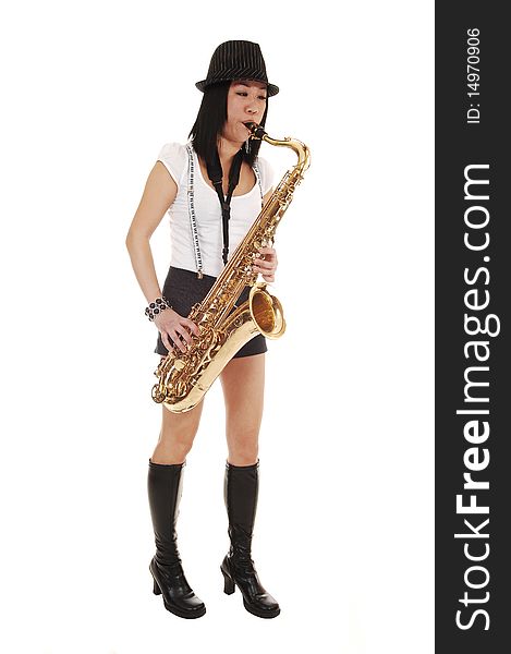 A young Asian woman standing in the studio, playing the saxophone in shorts with suspender and a hat on her black hair, for white background. A young Asian woman standing in the studio, playing the saxophone in shorts with suspender and a hat on her black hair, for white background.