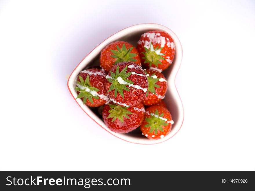 Fresh ripe strawberrys drizzled in cream in a heart shaped dish. Fresh ripe strawberrys drizzled in cream in a heart shaped dish