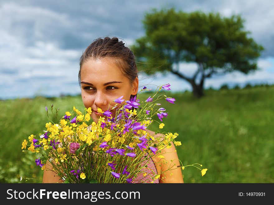 Beautiful girl is gathering bouquet in a field, summer