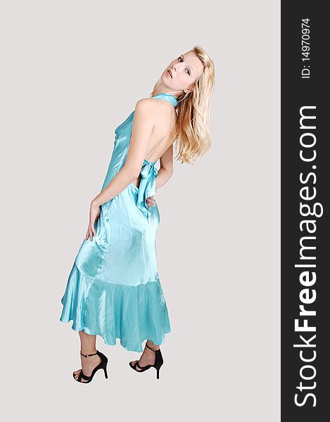 A beautiful tall blond woman in an light blue long dress and high heels
standing from the back in the studio for a portrait, on light gray background. A beautiful tall blond woman in an light blue long dress and high heels
standing from the back in the studio for a portrait, on light gray background.