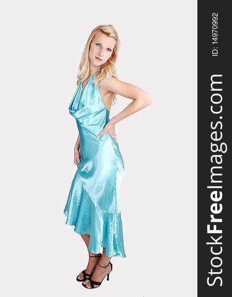 A beautiful tall blond woman in an light blue long dress and high heels standing from the site in the studio for a portrait, on light gray background. A beautiful tall blond woman in an light blue long dress and high heels standing from the site in the studio for a portrait, on light gray background.