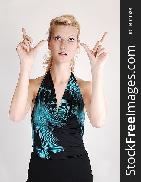 A beautiful blond woman holding her hands up and making
a sign to the photographer, on light gray background. A beautiful blond woman holding her hands up and making
a sign to the photographer, on light gray background.