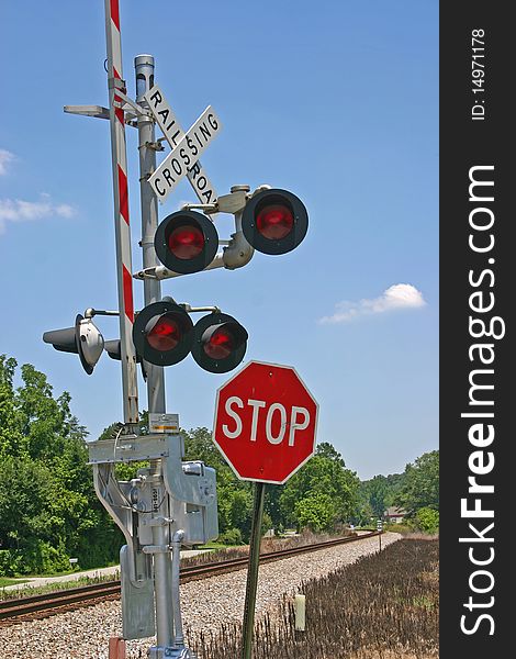 A railroad crossing gate and a stop sign near train tracks