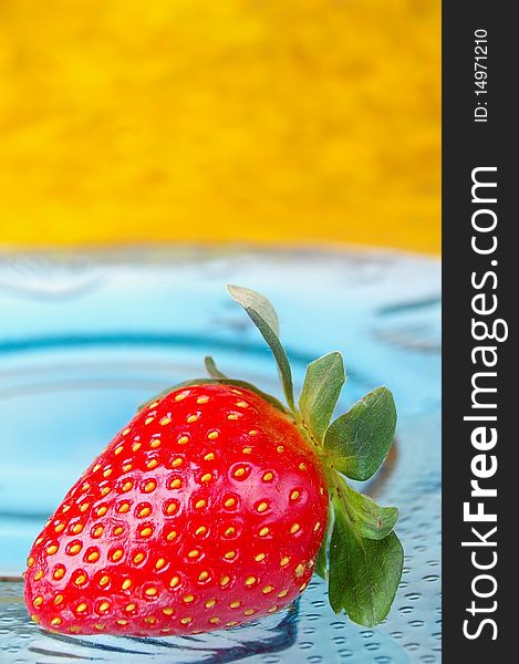 Single strawberry blue glass plate yellow background