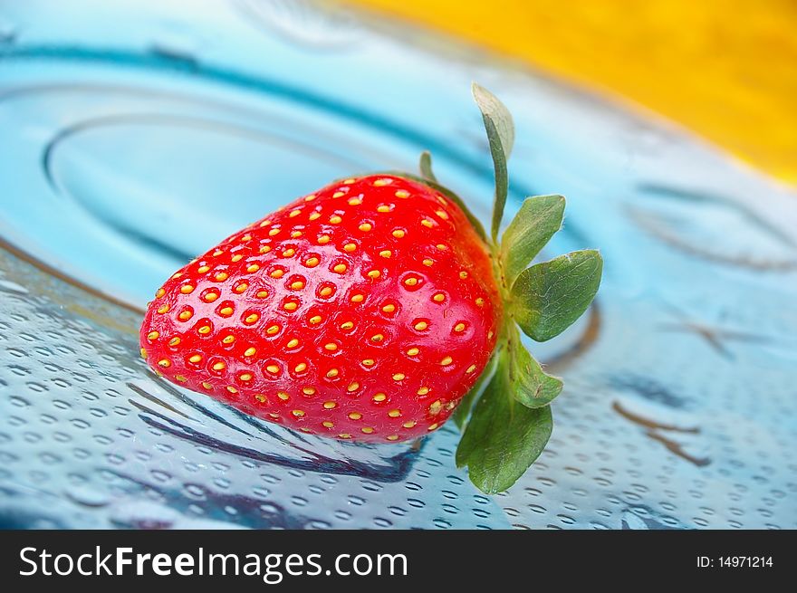 Single strawberry blue glass plate yellow background