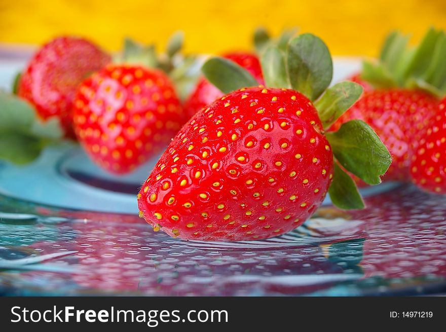 Pile of bright red strawberries on clourful background plate