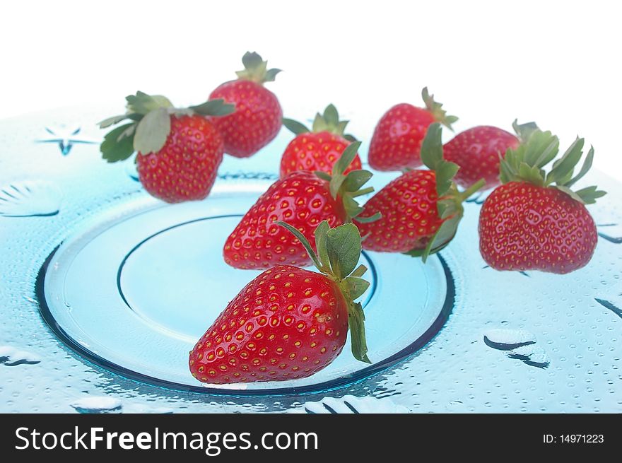 Pile of bright red ripe clean strawberries laid out on ble plate