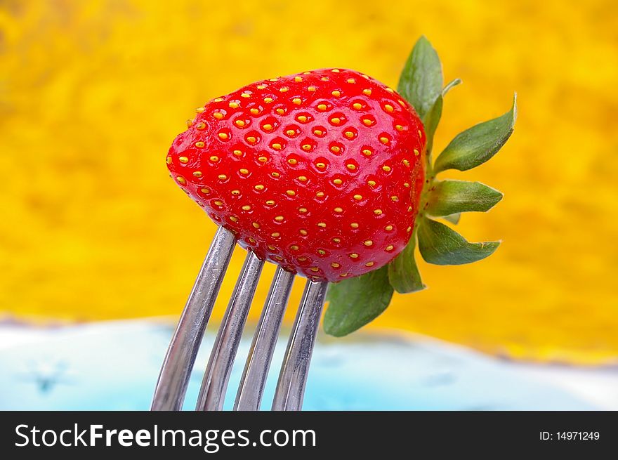 A single strawberry on a silver fork. A single strawberry on a silver fork