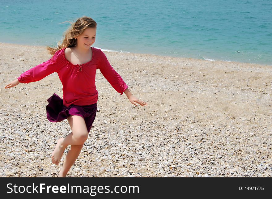 Little happy girl child in pink clothes running on the beach having great holiday fun