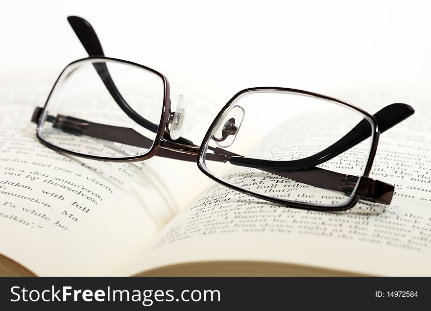 Reading glasses on an open book, closeup. Reading glasses on an open book, closeup