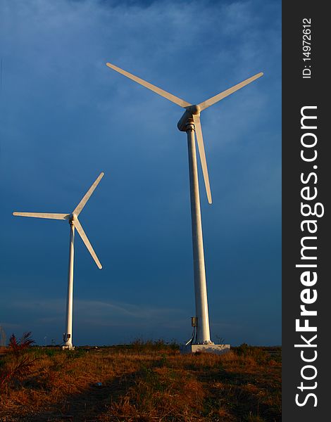 Modern wind turbines or wind mills in cloudy sky