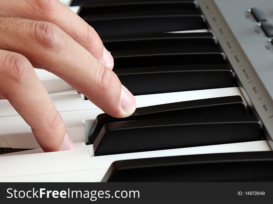 Closeup of a male hand playing on a piano keyboard. Closeup of a male hand playing on a piano keyboard