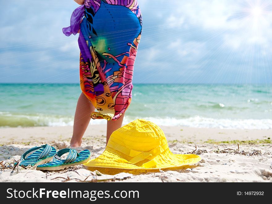 Flip-flop, hat and woman on the beach near sea. Focus on hat