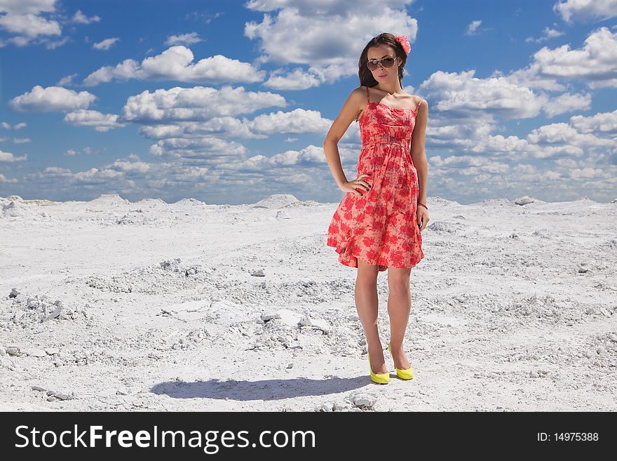 Cute young woman in red dress on the snow posing