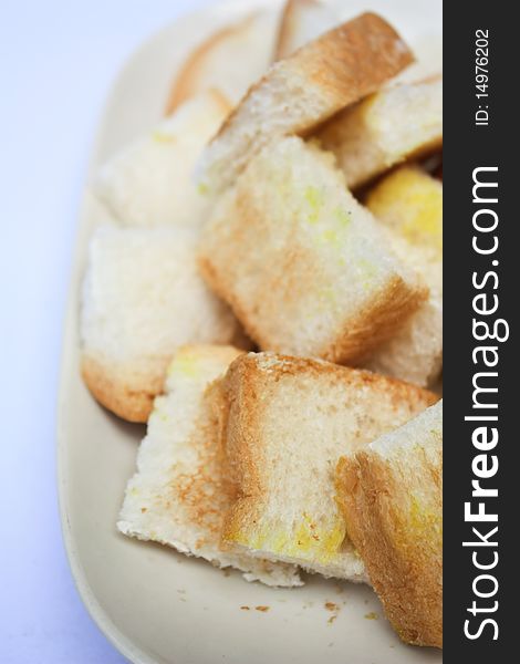 Toast cut in pieces on white plate white background close up