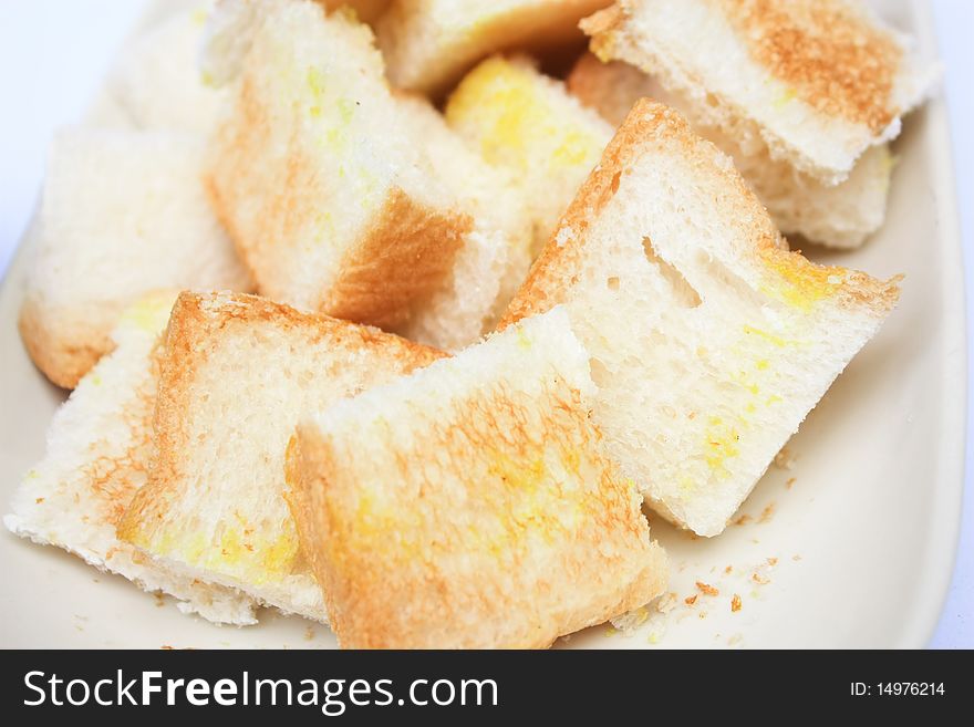 Toast cut in pieces on white plate white background close up