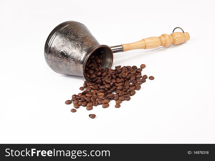 Coffee grains scattered near a coffee pot on a white background. Coffee grains scattered near a coffee pot on a white background