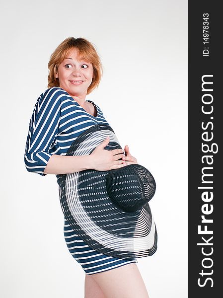 Funny pregnant woman hiding her belly behind a big sun-hat