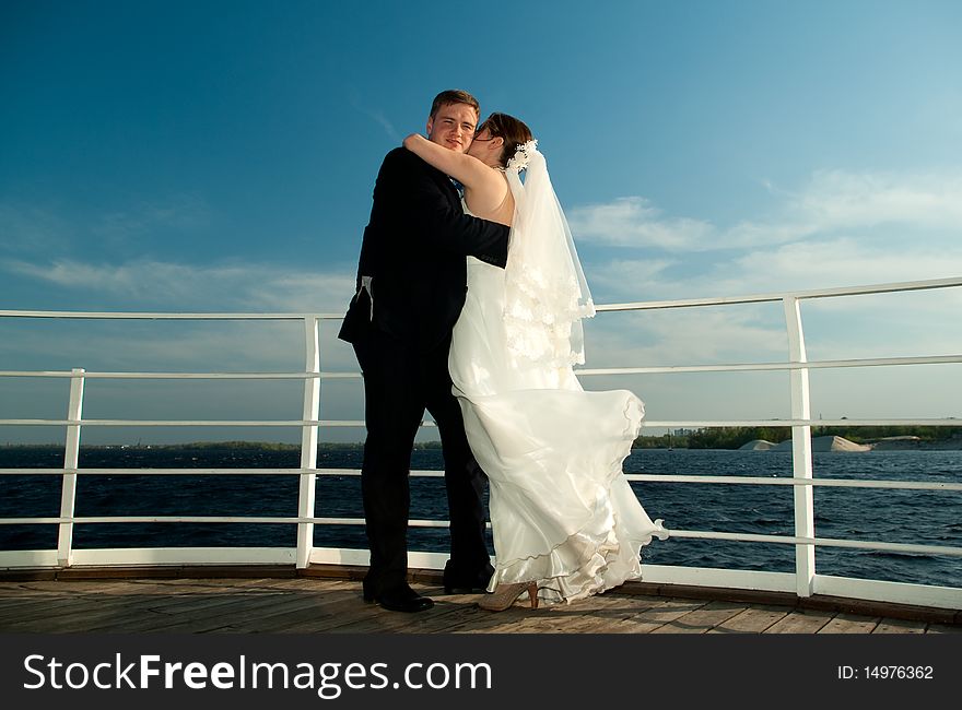Young beautiful bride embracing each other on the deck near the river. Young beautiful bride embracing each other on the deck near the river