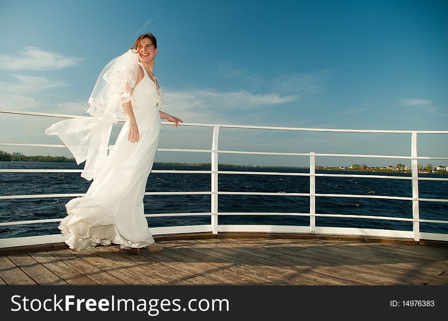 Young beautiful bride on the deck near the river. Young beautiful bride on the deck near the river