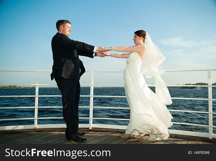 Beautiful young brie and groom holding hands at the deck on the river. Beautiful young brie and groom holding hands at the deck on the river