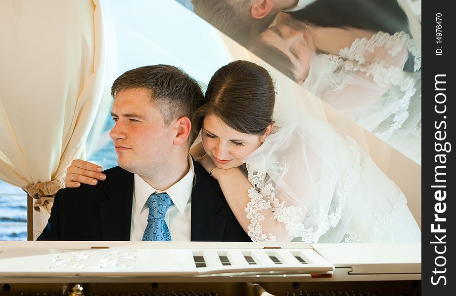 Young beautiful bride and groom at the white grand piano