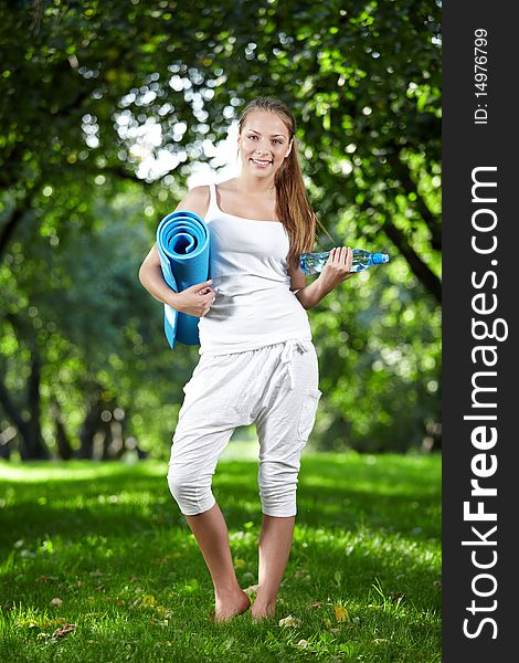 Young girl with a bottle of water and gymnastic mat. Young girl with a bottle of water and gymnastic mat