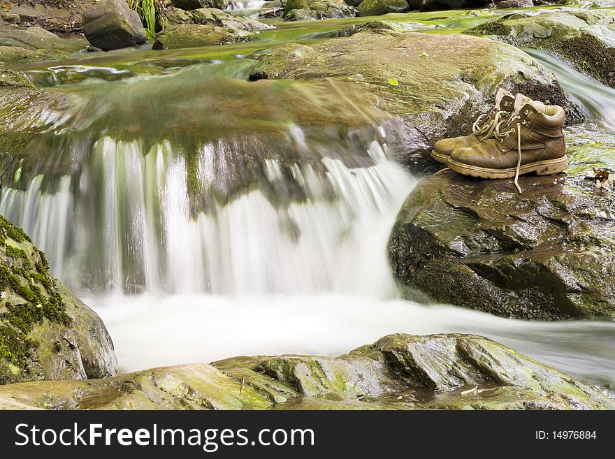 A pair of hiking boots at the waterfall.