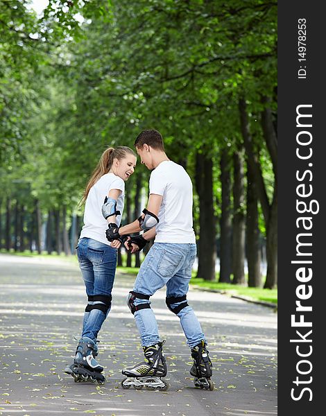 Young couple roller-skating in the park. Young couple roller-skating in the park