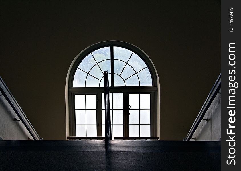 A set of stairs going downward with a large window and railings. A set of stairs going downward with a large window and railings.