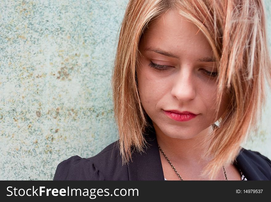 Thoughtful Attractive blonde girl by concrete wall