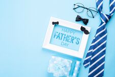 Happy Fathers Day Concept. Top View Of Blue Tie, Beautiful Gift Box, White Picture Frame With Happy Father`s Day Text On Bright Stock Photos