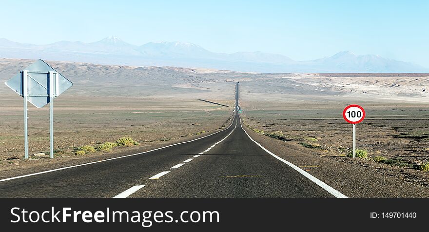 Desert road: A long straight road with road sign through the Atacama Desert, Chile